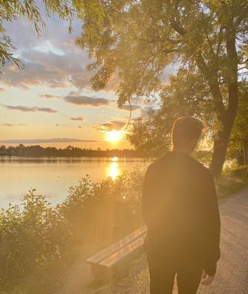 Ung man på promenad i solnedgången.