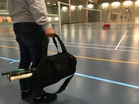 Mand står emd sportstaske i hånden i hallen inden badminton