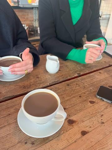 Tre veninder hygger sig på en café med hver deres kop kaffe, efter de har mødt hinanden på Boblberg