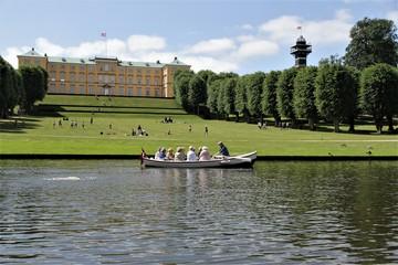 En smuk somemrdag i Frederiksberg Have, hvor nogle ældre damer sejler i en robåd på søen foran det flotte gule Frederiksberg Slot