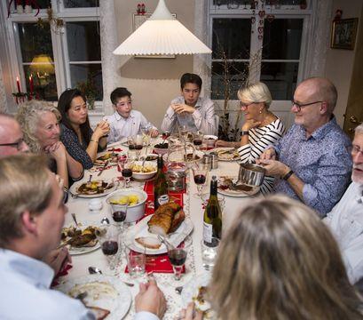 En masse mennesker sidder og spiser rundt om julebordet