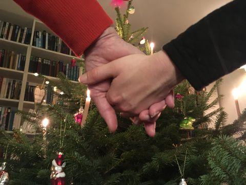 To personer holder hinanden i hænderne, imens de danser rundt om juletræet