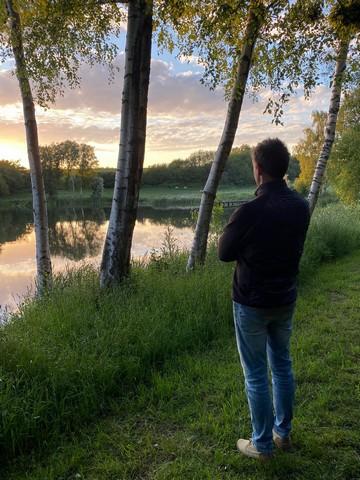 En man som står vid en vacker sjö och vacker natur.