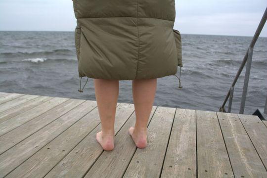 Kvinde står i dunjakke på badebroen