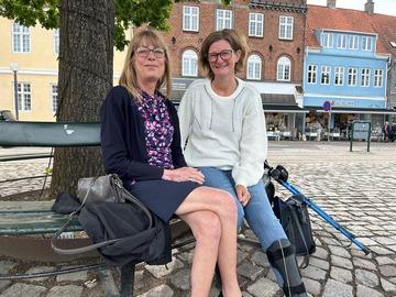 To kvinder, Heidi og Janne sidder på en bænk og smiler, fordi de har mødt hinanden på Boblberg og startet deres nye venskab her
