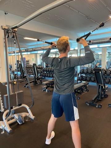 En ung fyr træner styrketræning i fitnesscenteret med en ny træningsmakker, som han har fundet på Boblberg