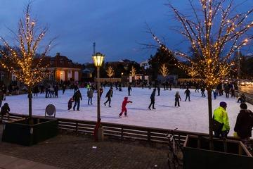 Børn og voksne skøjter på skøjtebanen på Frederiksberg Runddel en smuk vinteraften imens træerne rundt omkring skøjtebanen er lyst op med julelys