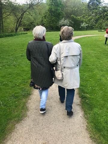En frivillig kvinde med kort blond hår og grøn jakke, er ude at gå en tur med en gammel dame med lys jakke, som hun er blevet ledsager for gennem Boblberg