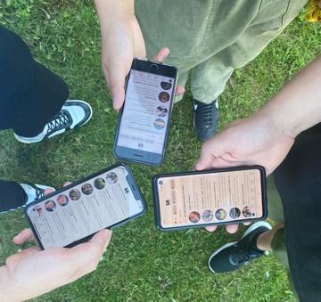 Tre personer står med deres telefoner i hånanden, og viser på skærmene at de er inde at finde nye fællesskaber på Boblberg